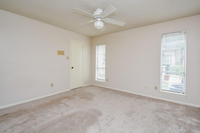 carpeted empty room with ceiling fan, a textured ceiling, and a wealth of natural light