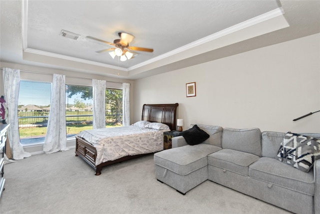 carpeted bedroom with a tray ceiling, ceiling fan, and crown molding