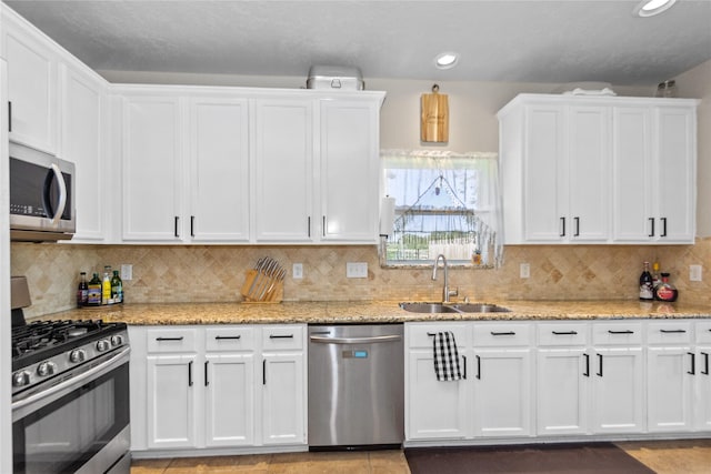 kitchen featuring white cabinets, sink, decorative backsplash, appliances with stainless steel finishes, and light stone counters