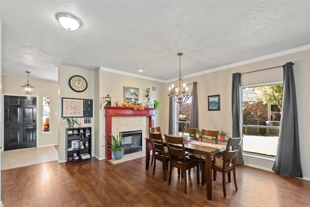 dining room with a tile fireplace, a textured ceiling, hardwood / wood-style flooring, and crown molding