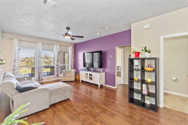 living room with hardwood / wood-style flooring, ceiling fan, and a textured ceiling