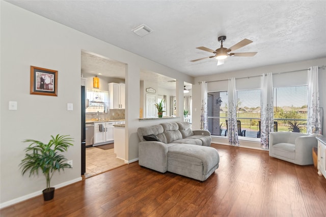 living room featuring ceiling fan, dark hardwood / wood-style floors, and a textured ceiling