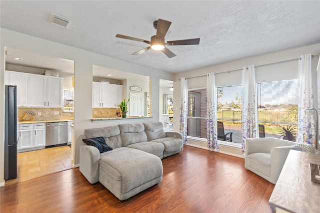 living room with hardwood / wood-style floors, ceiling fan, and a textured ceiling