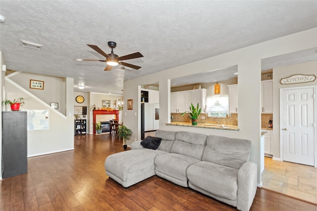 living room featuring a textured ceiling, dark hardwood / wood-style floors, ceiling fan, and sink