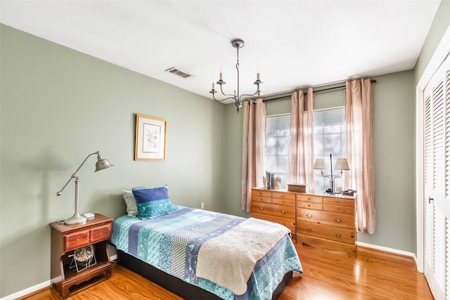 bedroom featuring a closet, a chandelier, and hardwood / wood-style flooring