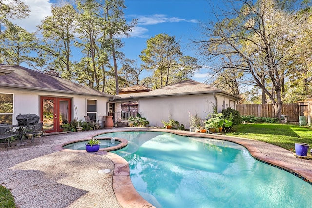 view of pool with french doors, a yard, an in ground hot tub, a grill, and a patio area