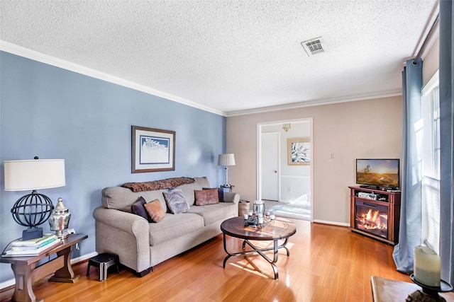 living room with a textured ceiling, light hardwood / wood-style flooring, and ornamental molding