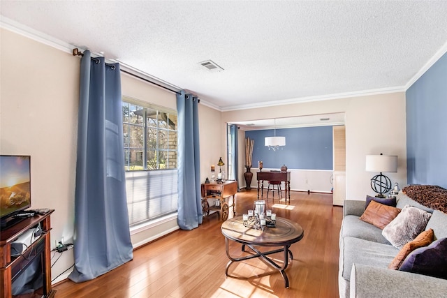 living room featuring a textured ceiling, crown molding, hardwood / wood-style floors, and plenty of natural light