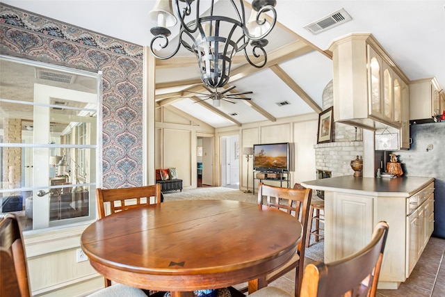 dining space featuring lofted ceiling with beams and ceiling fan with notable chandelier