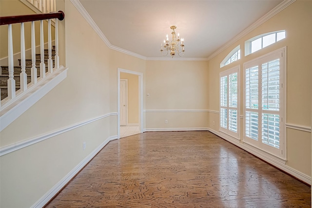 spare room with hardwood / wood-style flooring, ornamental molding, and a chandelier