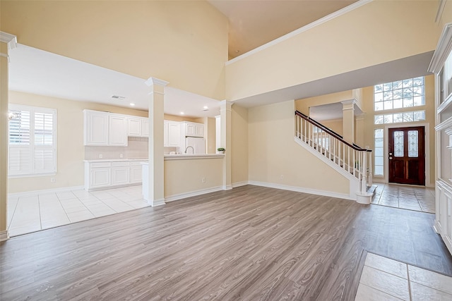 unfurnished living room with light hardwood / wood-style floors and a high ceiling