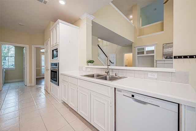 kitchen with sink, stainless steel appliances, light tile patterned floors, kitchen peninsula, and white cabinets