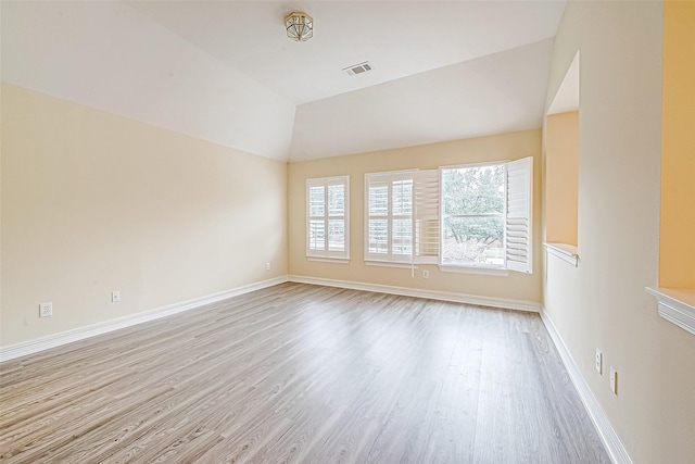 spare room with lofted ceiling and light wood-type flooring