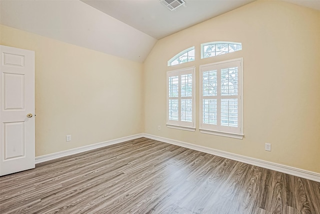 spare room featuring light hardwood / wood-style floors and vaulted ceiling