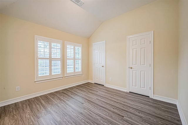 unfurnished bedroom with hardwood / wood-style floors and lofted ceiling