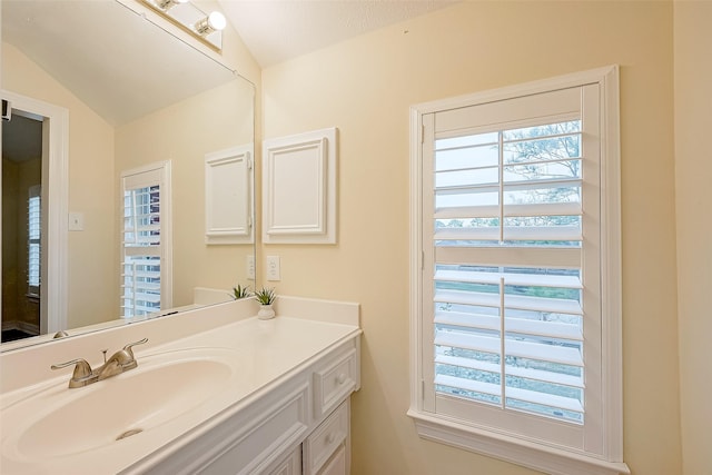 bathroom with vanity, a textured ceiling, and vaulted ceiling