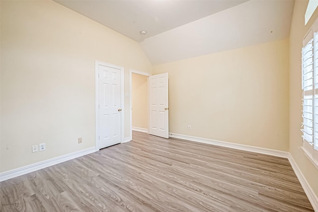 empty room featuring lofted ceiling and light hardwood / wood-style flooring