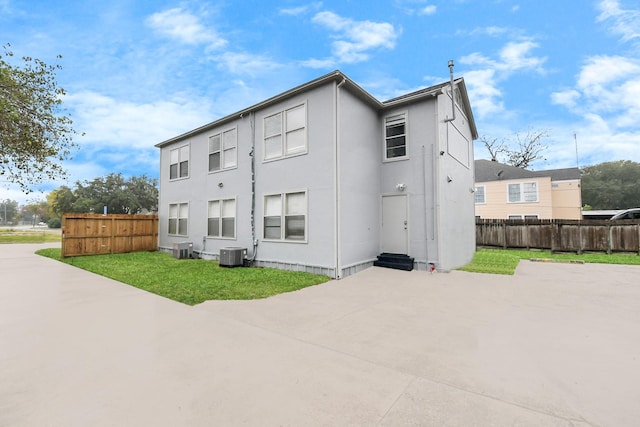 back of house with central AC and a yard