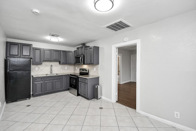 kitchen with gray cabinetry, sink, decorative backsplash, light stone countertops, and appliances with stainless steel finishes