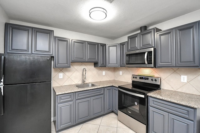 kitchen with backsplash, light tile patterned floors, sink, and appliances with stainless steel finishes