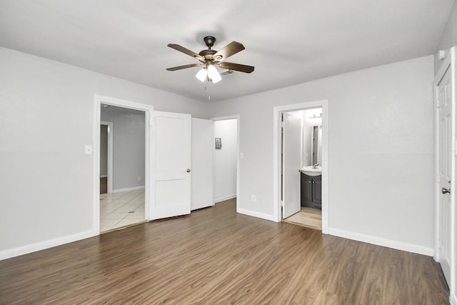 unfurnished bedroom with ceiling fan, dark wood-type flooring, and ensuite bath