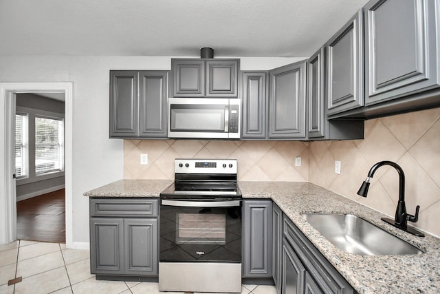 kitchen featuring gray cabinets, sink, light tile patterned floors, and stainless steel appliances