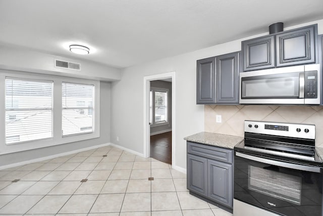 kitchen featuring a healthy amount of sunlight, light tile patterned floors, appliances with stainless steel finishes, and tasteful backsplash