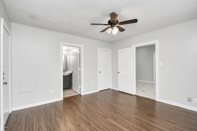 unfurnished bedroom with ceiling fan, dark wood-type flooring, and connected bathroom