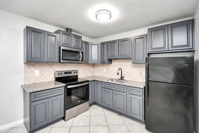 kitchen featuring sink, decorative backsplash, gray cabinets, light tile patterned floors, and appliances with stainless steel finishes