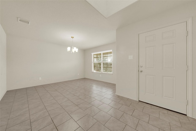 tiled spare room with a chandelier