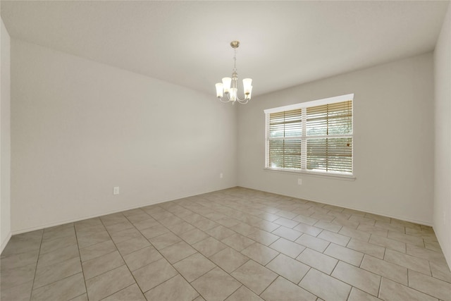 tiled spare room featuring a chandelier