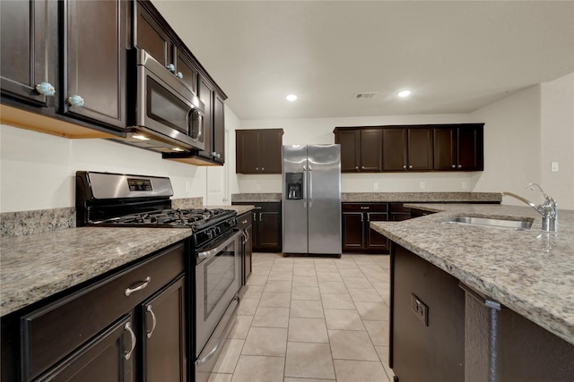 kitchen featuring light stone countertops, appliances with stainless steel finishes, light tile patterned floors, and sink