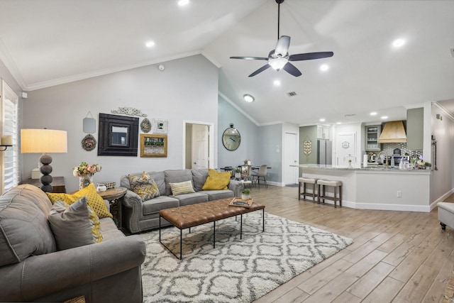 living room with lofted ceiling, light wood-type flooring, ceiling fan, and crown molding