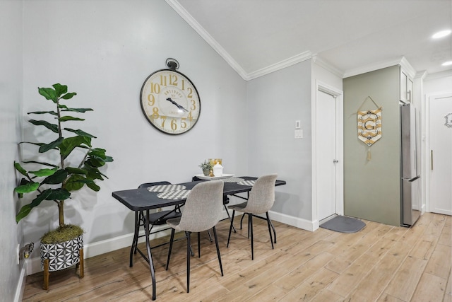 dining area with lofted ceiling, ornamental molding, and light hardwood / wood-style flooring