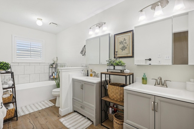 bathroom with hardwood / wood-style floors, vanity, toilet, and a bathing tub