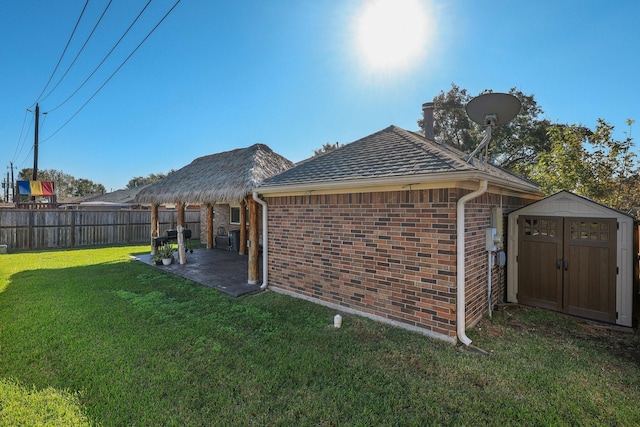 view of side of property with a patio area, a yard, and a storage unit