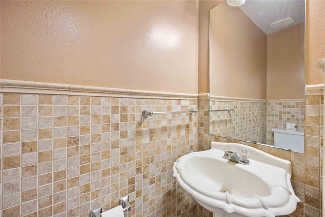 bathroom with sink, tile walls, and toilet