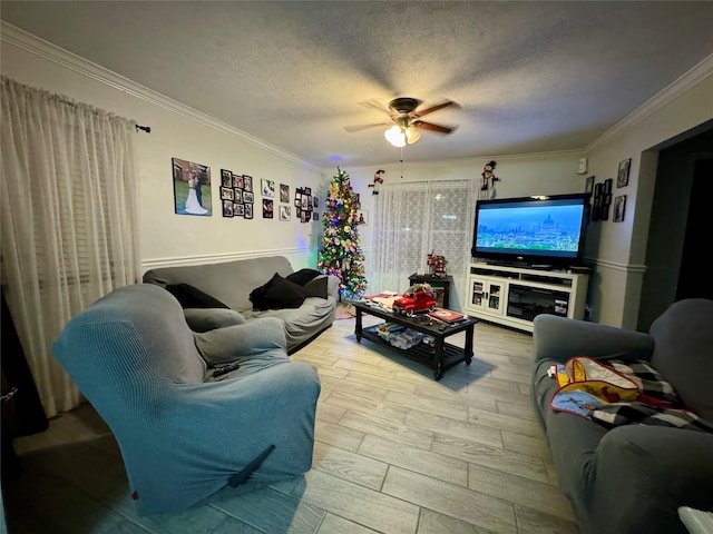 living room with ceiling fan, ornamental molding, a textured ceiling, and light hardwood / wood-style flooring