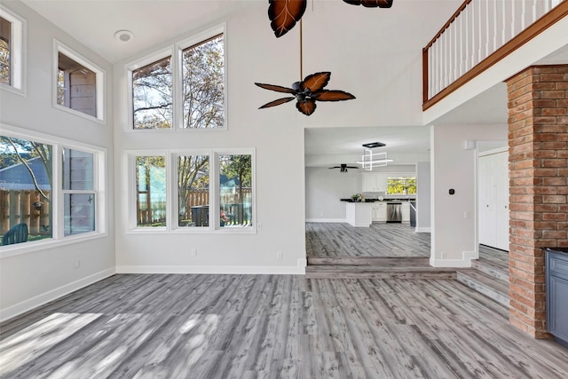 unfurnished living room featuring light wood-type flooring, a towering ceiling, and plenty of natural light