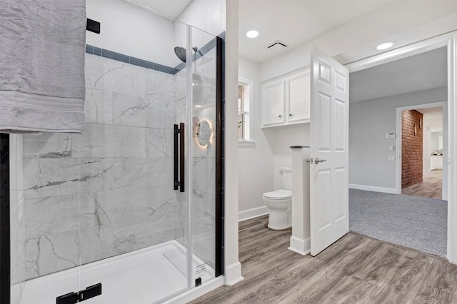 bathroom with wood-type flooring, toilet, and walk in shower