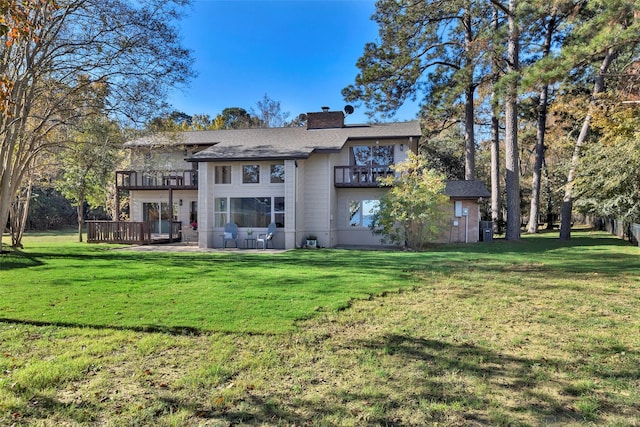 rear view of house with a lawn and a balcony