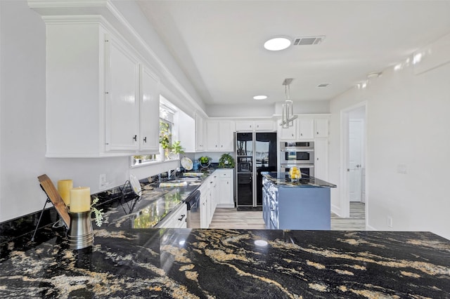 kitchen featuring dark stone countertops, white cabinetry, light hardwood / wood-style floors, and appliances with stainless steel finishes