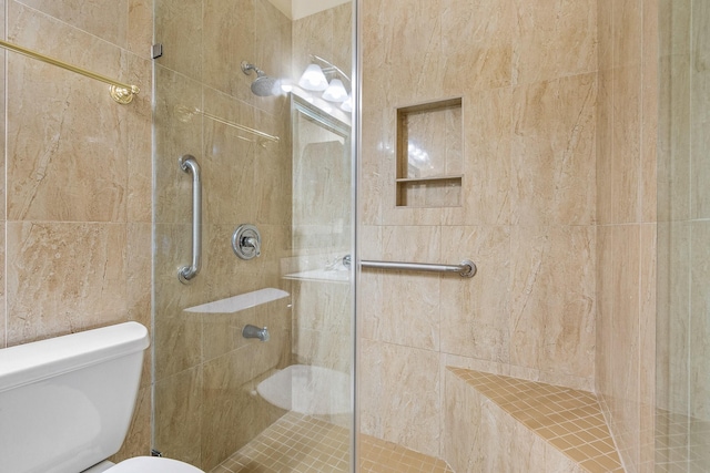 bathroom with a tile shower and toilet