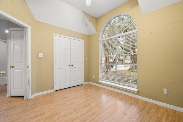 unfurnished bedroom with light hardwood / wood-style floors, a closet, and lofted ceiling