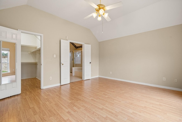 unfurnished bedroom with ceiling fan, light hardwood / wood-style floors, vaulted ceiling, a walk in closet, and a closet