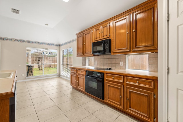 kitchen with vaulted ceiling, black appliances, decorative light fixtures, a notable chandelier, and light tile patterned flooring