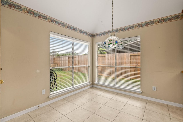 unfurnished dining area with light tile patterned flooring, lofted ceiling, and a notable chandelier