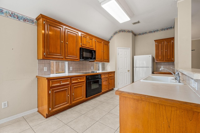 kitchen featuring light tile patterned floors, sink, vaulted ceiling, and black appliances