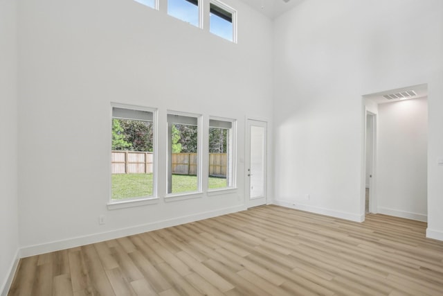 unfurnished room featuring a high ceiling and light hardwood / wood-style floors