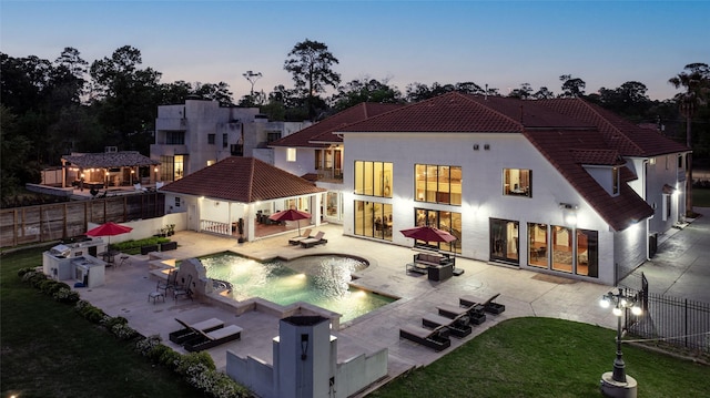 back house at dusk with a fenced in pool and a patio